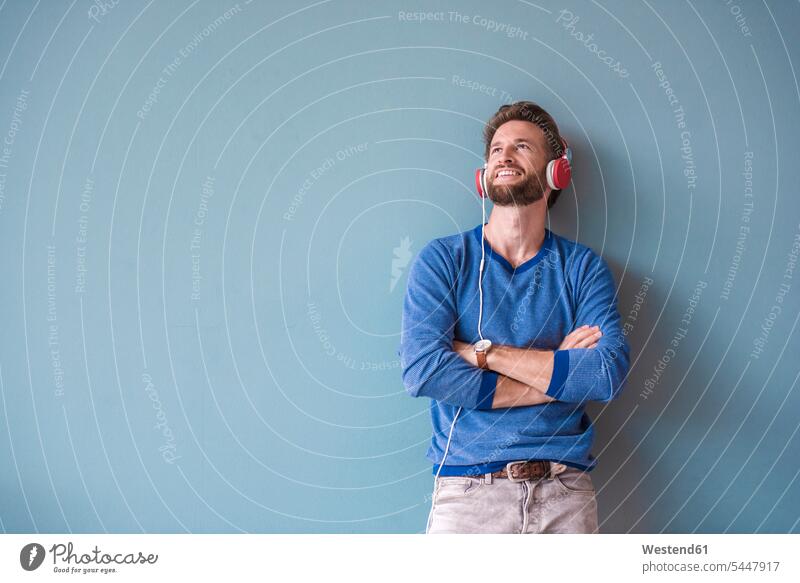Smiling man listening to music with headphones headset relaxed relaxation hearing smiling smile wall walls relaxing beard looking up Joy enjoyment pleasure