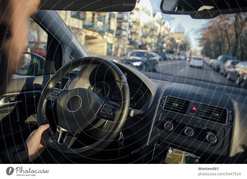 Steering wheel and hand of a man driving a car through the city steering car driver car driving motoring sunlight Sunlit automobile Auto cars motorcars