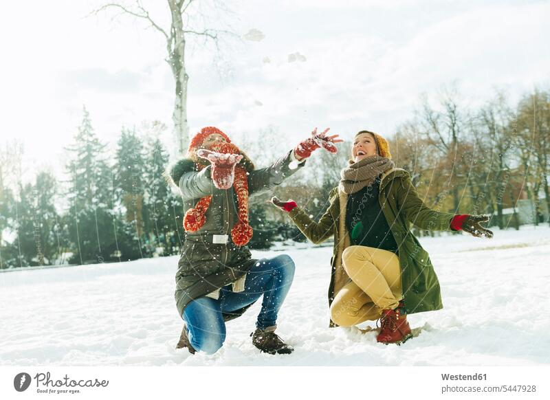Two best friends having fun in the snow female friends mate friendship laughing Laughter snow-covered snow covered covered in snow snowy crouching cowering