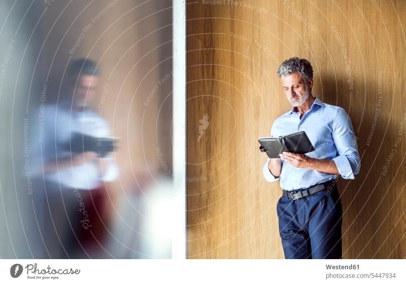 Reflection of mature businessman standing at wooden wall looking in diary schedule timetable Businessman Business man Businessmen Business men wooden walls