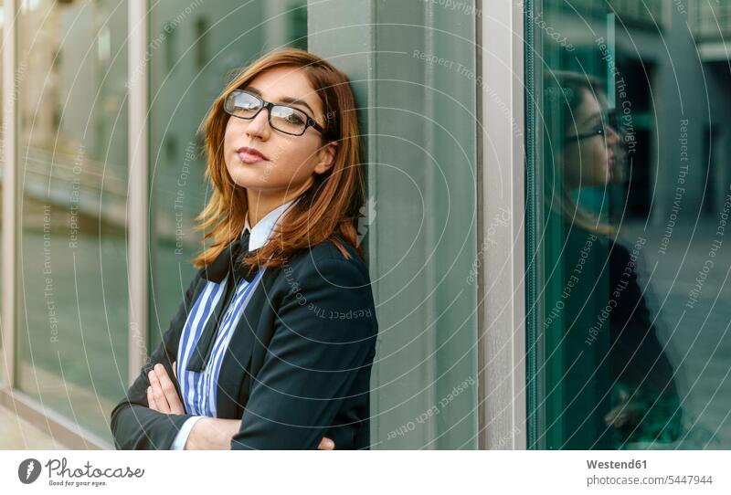 Businesswoman leaning against window with arms crossed tired glasses specs Eye Glasses spectacles Eyeglasses serious earnest Seriousness austere businesswoman