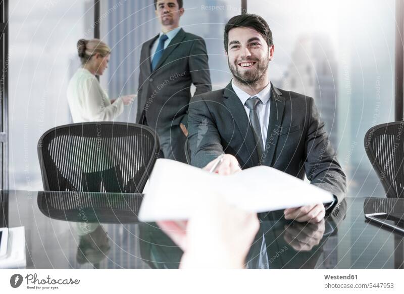 Businessman receiving paper in city office giving give smiling smile offices office room office rooms Business man Businessmen Business men colleagues workplace