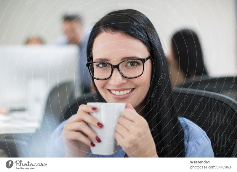 Employee enjoying a cup of coffee at her desk office offices office room office rooms workplace work place place of work smiling smile Coffee woman females