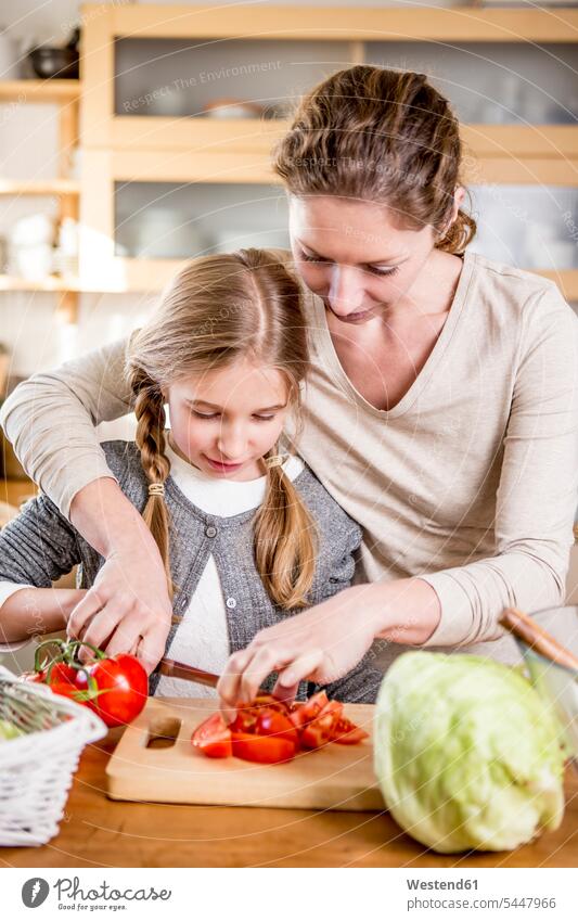 Mother and daughter cutting tomatoes in kitchen daughters mother mommy mothers mummy mama Tomato Tomatoes domestic kitchen kitchens child children family