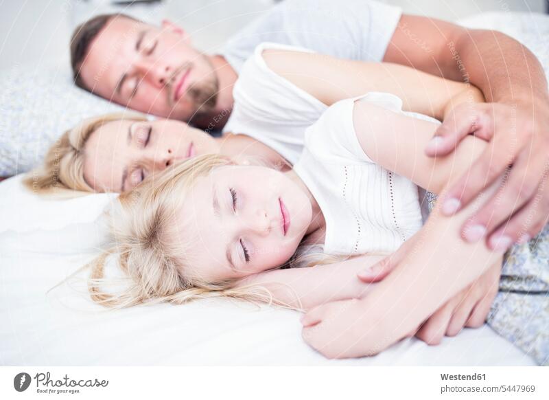 Family sleeping in bed daughter daughters beds lying laying down lie lying down asleep family families child children people persons human being humans