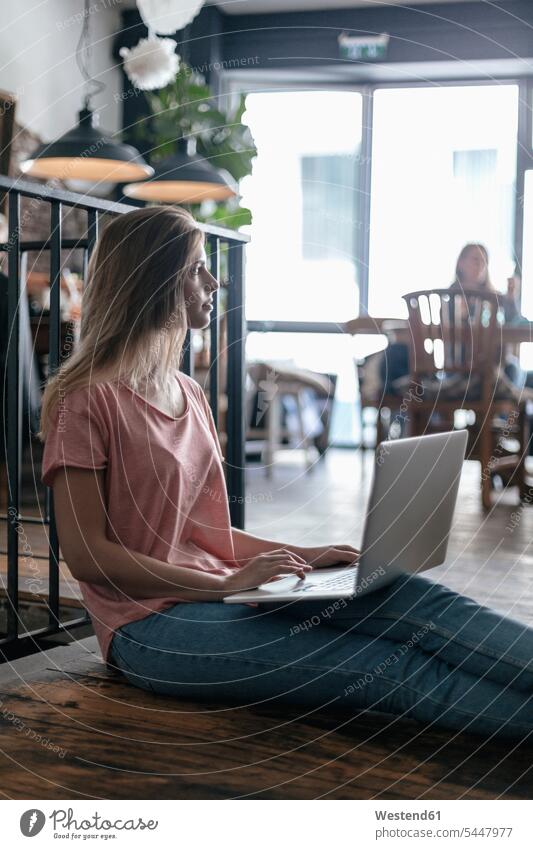Young woman sitting in cafe, using laptop Laptop Computers laptops notebook Seated working At Work young females women thinking computer computers Adults