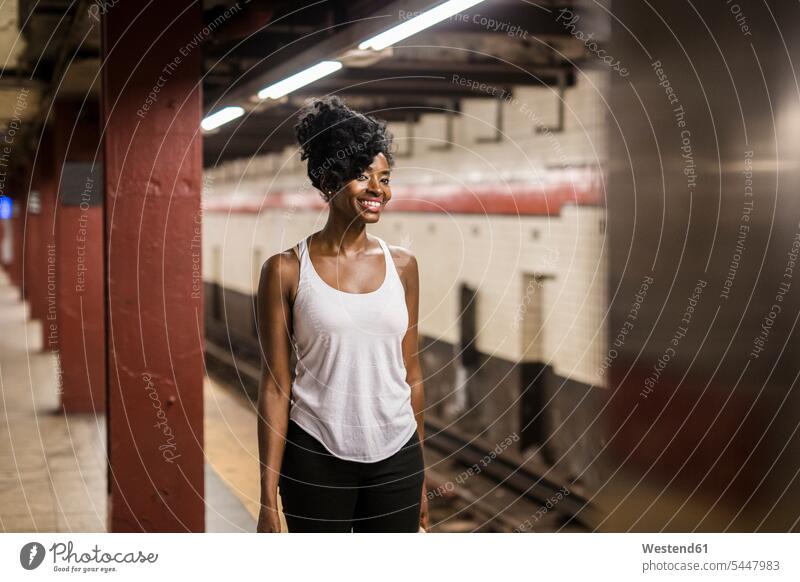 USA, New York City, Manhattan, smiling woman waiting at subway station platform underground station platform Subway Platform females women underground stations