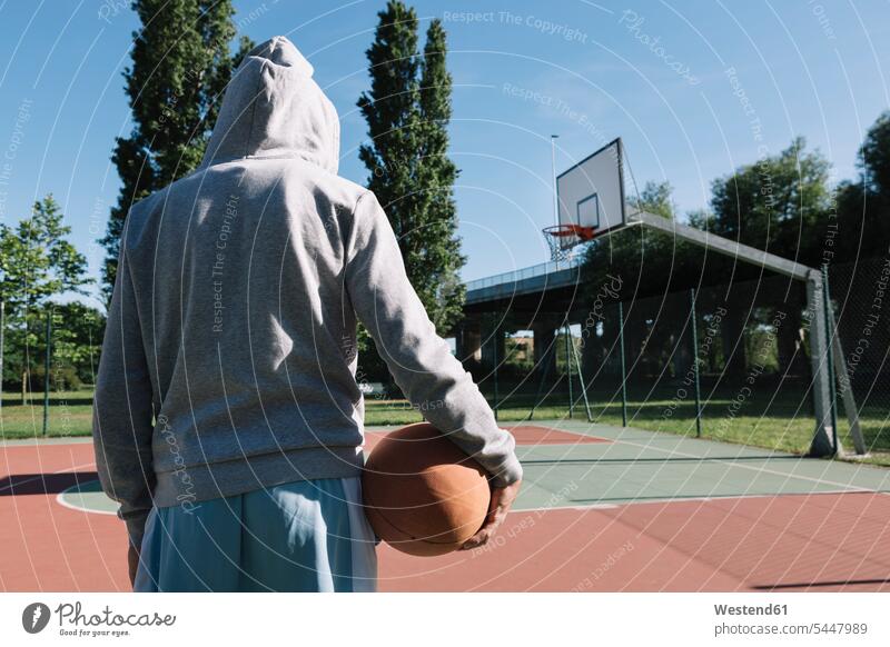 Man holding basketball, hoop in the background basketballs basketball player basketball players sport sports man men males leisure free time leisure time