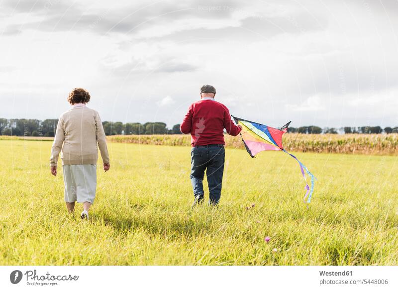 Senior couple walking with kite in rural landscape twosomes partnership couples senior women elder women elder woman old senior woman senior men senior man