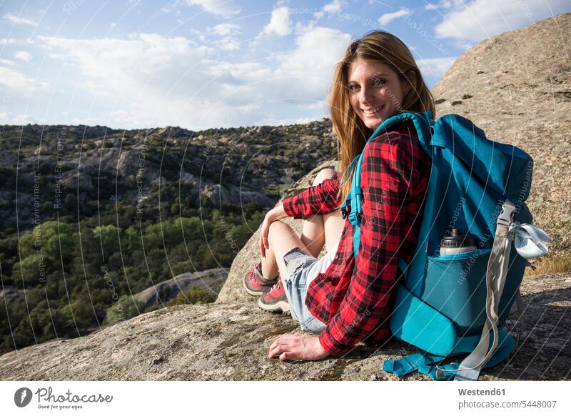 Spain, Madrid, smiling young woman resting on a rock during a trekking day females women hiking hike mountain mountains rocks sitting Seated smile Adults