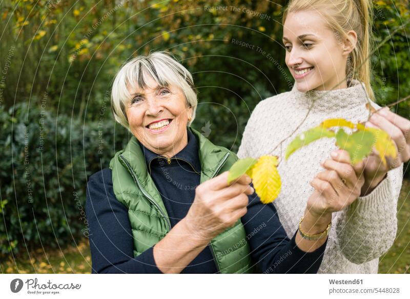 Happy young woman with her grandmother holding twig in garden grandmas grandmothers granny grannies happiness happy gardens females women Twig Twigs sprig