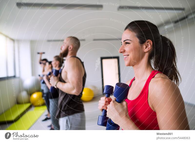 Group of athletes exercising with dumbbells in gym dumb-bells gyms Health Club smiling smile exercise training practising sport sports fitness Fitness