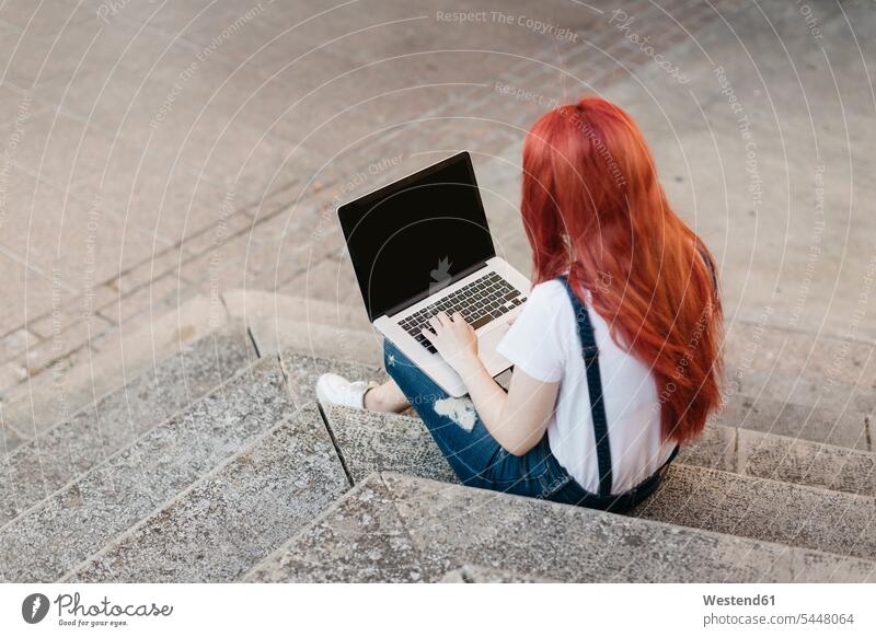 Redheaded woman sitting on stairs using laptop Laptop Computers laptops notebook females women computer computers Adults grown-ups grownups adult people persons