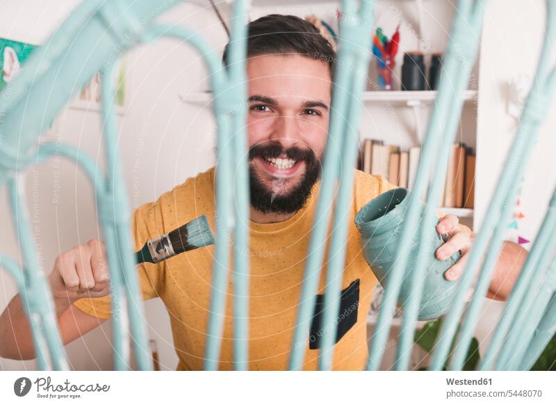 Portrait of smiling man painting wicker armchair at home smile chairs men males Adults grown-ups grownups adult people persons human being humans human beings