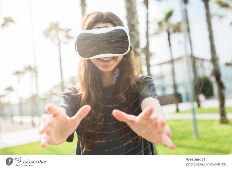 Young woman wearing VR glasses outdoors laughing Laughter virtual reality females women positive Emotion Feeling Feelings Sentiments Emotions emotional Adults