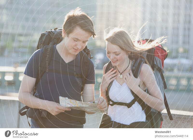 Germany, Berlin, Young couple traveling Berlin with backpacks, looking at map Traveller Travellers Travelers Sightseeing visiting viewing Teenager Teens