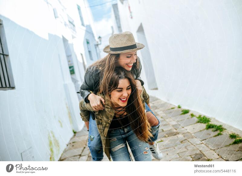 Happy young woman giving friend a piggyback ride Fun having fun funny female friends laughing Laughter mate friendship positive Emotion Feeling Feelings