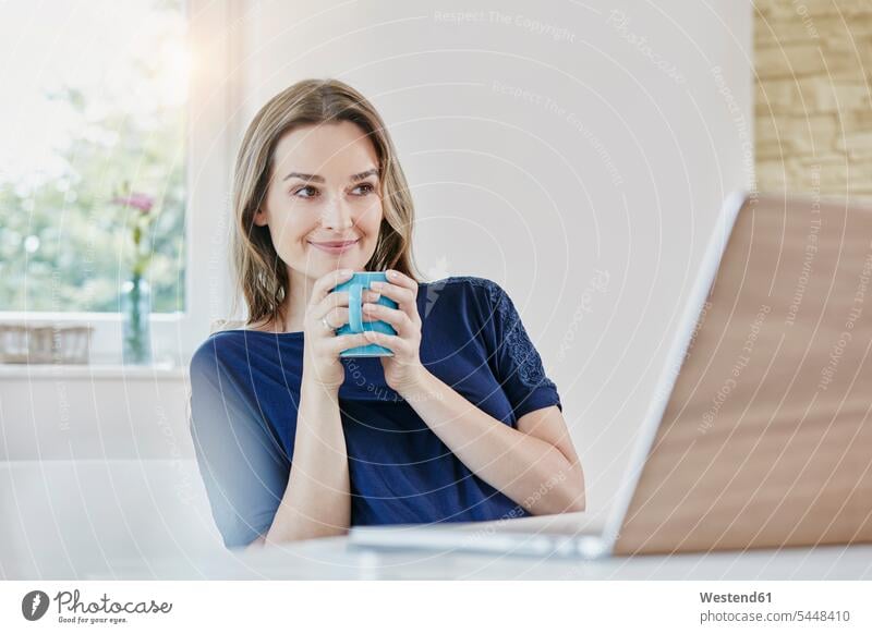 Smiling woman at home with coffee mug and laptop Laptop Computers laptops notebook females women smiling smile Coffee computer computers Adults grown-ups