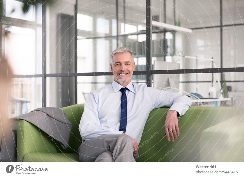 Mature businessman sitting on a couch in the office caucasian caucasian ethnicity caucasian appearance european conversation pit three-quarter length