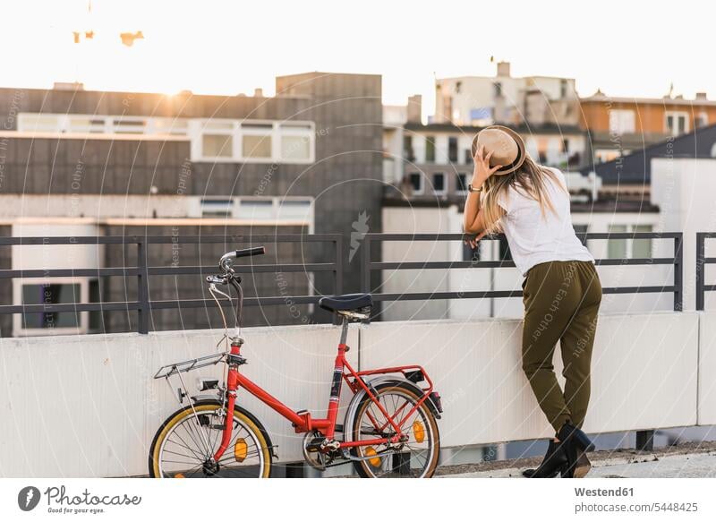 Young woman with bicycle leaning against railing city town cities towns Railing Railings females women bikes bicycles outdoors outdoor shots location shot