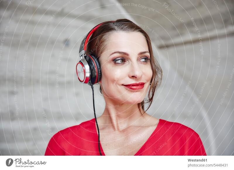 Smiling woman listening to music with headphones headset females women hearing smiling smile Adults grown-ups grownups adult people persons human being humans