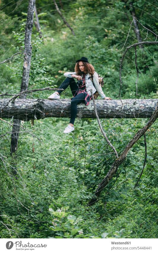 Teenage girl with camera sitting on deadwood in nature Teenage Girls female teenagers forest woods forests Teenager Teens people persons human being humans