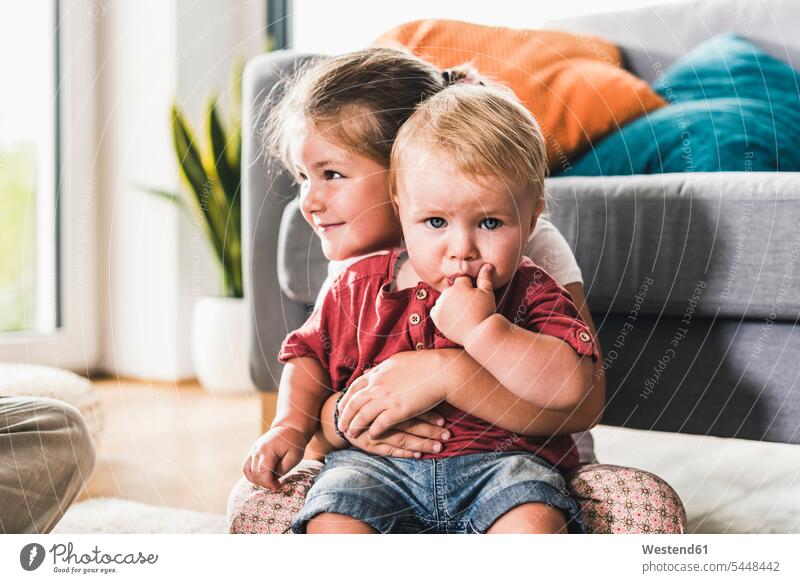 Brother and sister at home in living room embracing embrace Embracement hug hugging 12-17 months twelve to seventeen months 12 to 17 months 25-30 years 25 to 30