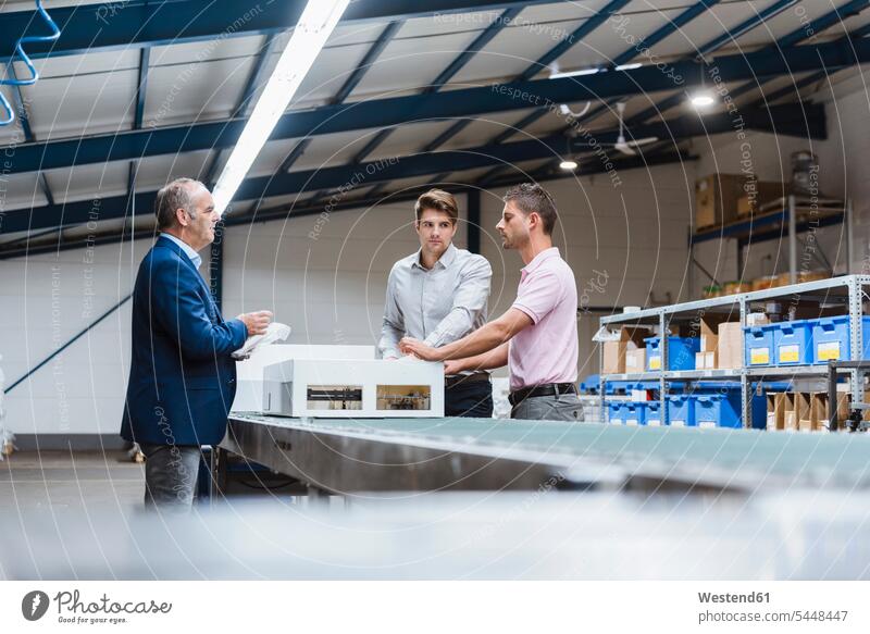 Business people standing on shop floor, discussing product improvement products Meeting Meetings Business Meeting business people businesspeople Quality