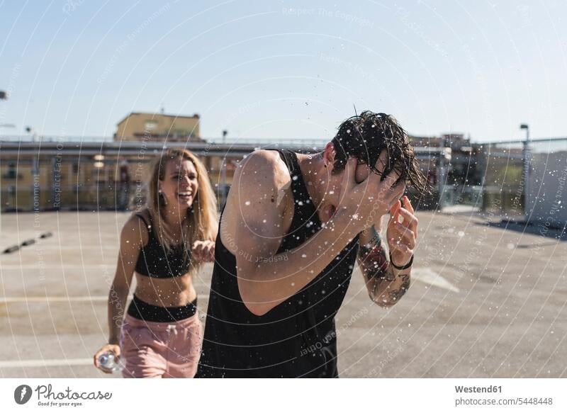 Young man getting splashed by his girlfriend couple twosomes partnership couples people persons human being humans human beings cheerful gaiety Joyous glad