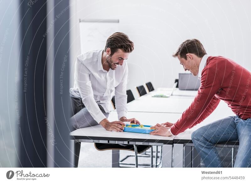 Two colleagues in office playing foosball table football table soccer offices office room office rooms laughing Laughter Businessman Business man Businessmen