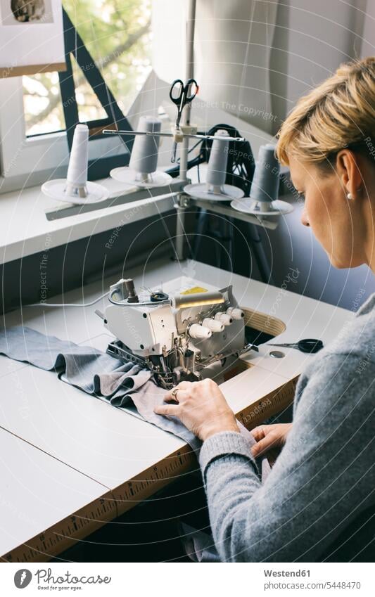 Woman using sewing machine on table in studio woman females women working At Work sewing machines seamstress seamstresses Adults grown-ups grownups adult people