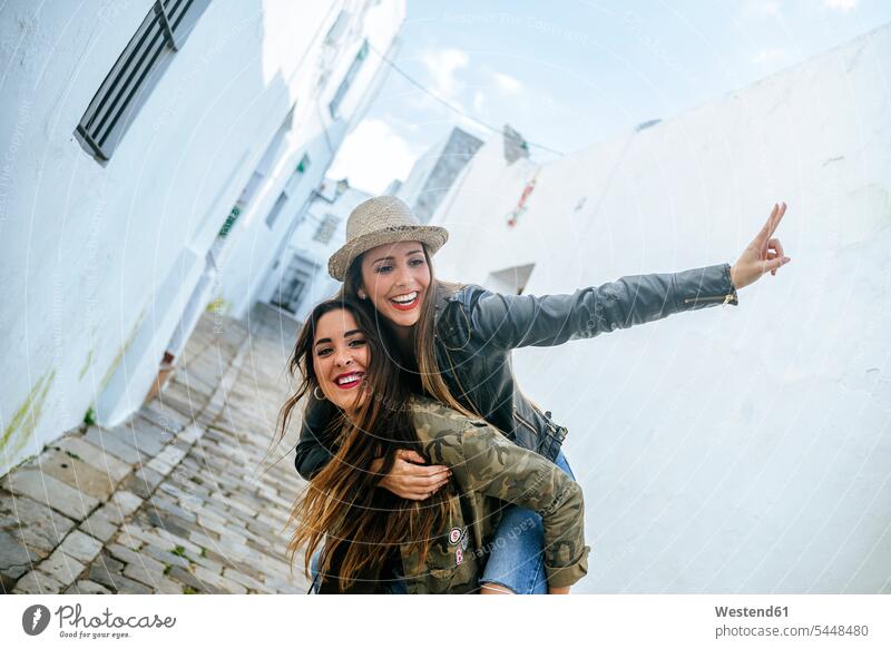 Happy young woman giving friend a piggyback ride Fun having fun funny female friends laughing Laughter mate friendship positive Emotion Feeling Feelings