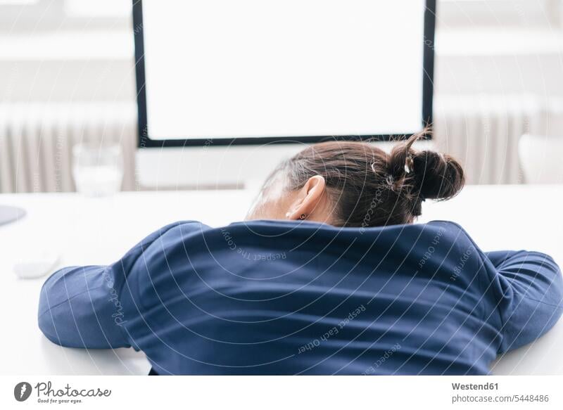 Back view of overworked woman sleeping on desk in office offices office room office rooms businesswoman businesswomen business woman business women females
