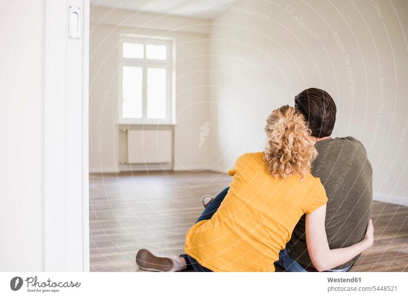Young couple in new home sitting on floor flat flats apartment apartments Seated twosomes partnership couples people persons human being humans human beings