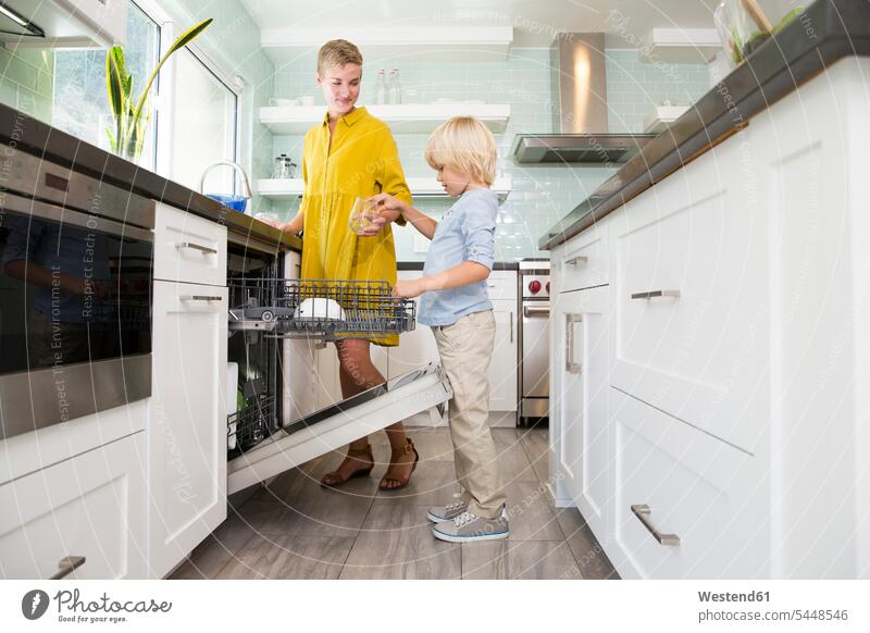 Boy helping mother clearing the dishwasher in kitchen son sons manchild manchildren assistance assisting Help mommy mothers mummy mama boy boys males