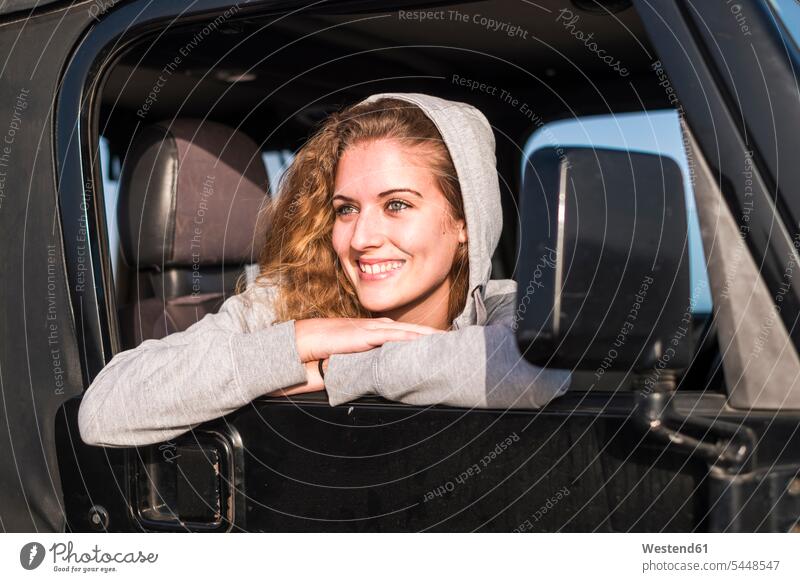 Portrait of happy young woman leaning out of car window portrait portraits females women automobile Auto cars motorcars Automobiles Adults grown-ups grownups