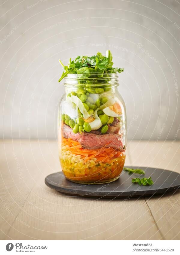 Preserving jar of wheat salad with vegetables, boiled egg and sliced steak plate wooden boiled eggs Vegetable Vegetables Wheat Triticum sativum Leaf Leaves