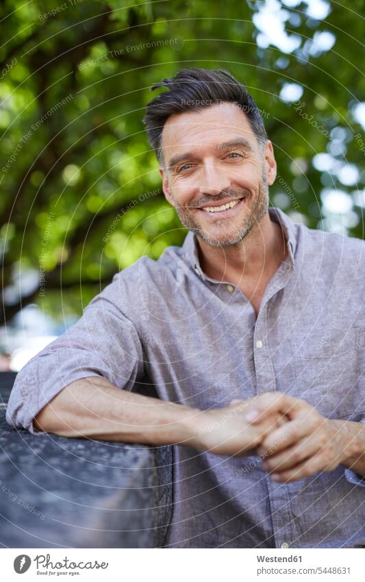 Portrait of laughing mature man leaning on a wall portrait portraits men males Adults grown-ups grownups adult people persons human being humans human beings