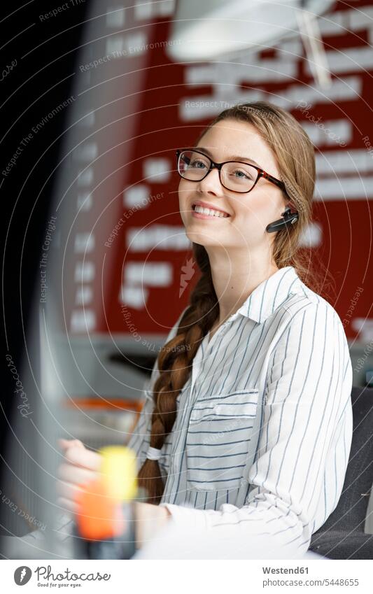 Smiling young woman in office wearing headset offices office room office rooms headsets smiling smile workplace work place place of work communication
