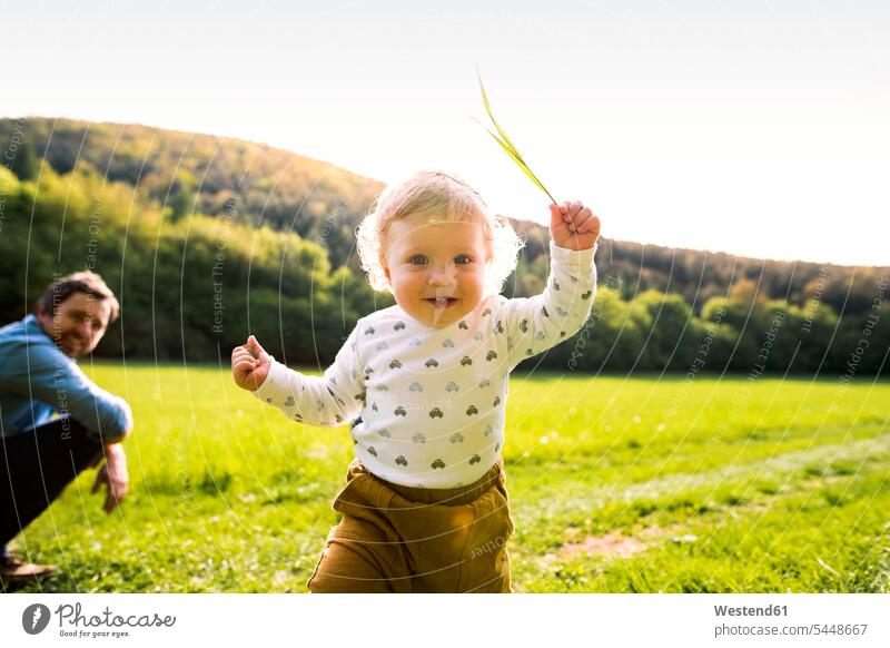 Cute little boy on meadow with father in background baby infants nurselings babies pa fathers daddy dads papa Fun having fun funny people persons human being