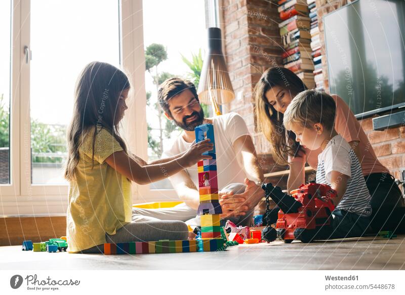 Family playing with building blocks on the floor together family families people persons human being humans human beings home at home four people 4