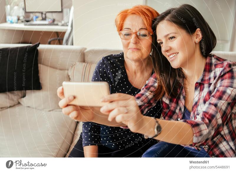 Adult daughter with mother at home taking a selfie mobile phone mobiles mobile phones Cellphone cell phone cell phones mommy mothers ma mummy mama woman females