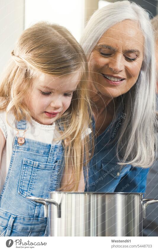 Grandmother and granddaughter cooking together, looking at pot grandmother grandmas grandmothers granny grannies granddaughters pots view seeing viewing kitchen