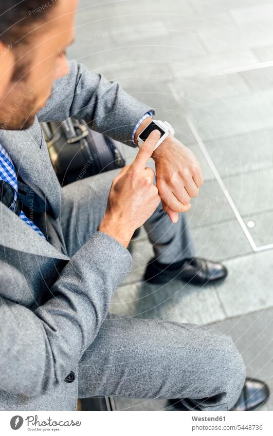 Close-up of businessman using his smartwatch in the city sitting Seated wrist watch Wristwatch Wristwatches wrist watches Businessman Business man Businessmen