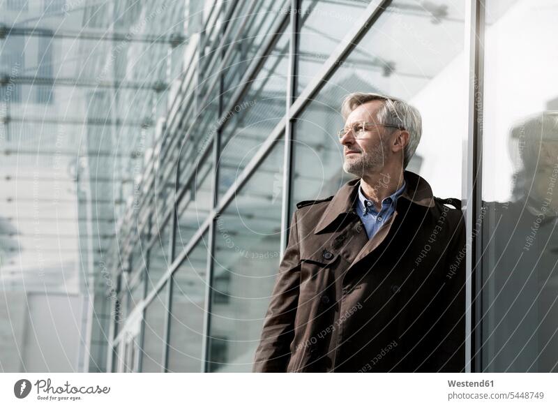 Grey-haired businessman standing at glass wall Businessman Business man Businessmen Business men business people businesspeople business world business life