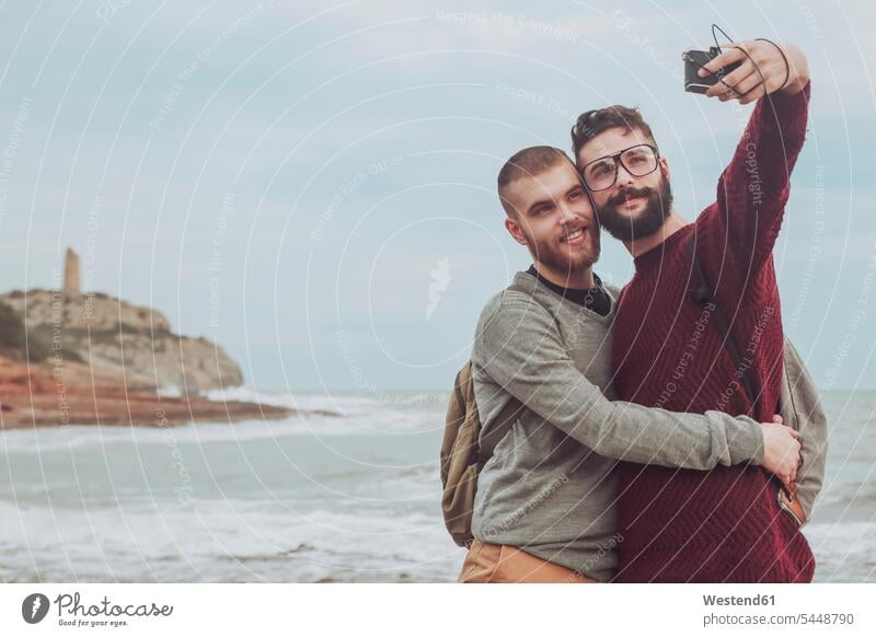 Spain, Oropesa del Mar, gay couple taking selfie in front of the sea Selfie Selfies twosomes partnership couples people persons human being humans human beings