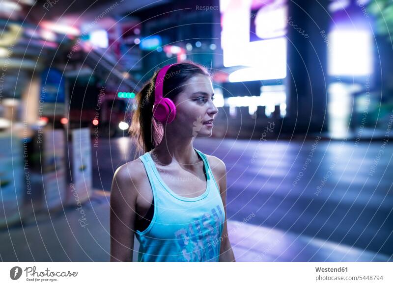 Young woman in pink sportshirt in modern urban setting at night exercising exercise training practising young women young woman on the phone call telephoning