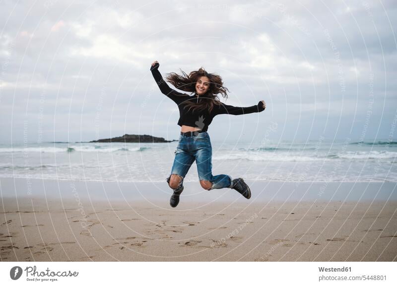 Happy woman jumping in the air on the beach beaches jump for joy jumping for joy females women Joy enjoyment pleasure Pleasant delight Adults grown-ups grownups