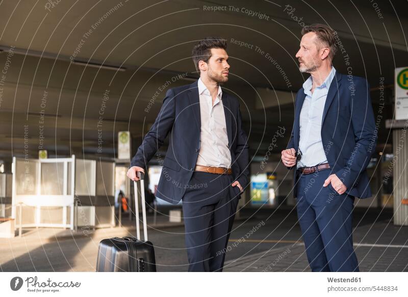 Two businessmen with rolling suitcase standing at bus terminal Businessman Business man Businessmen Business men business people businesspeople business world