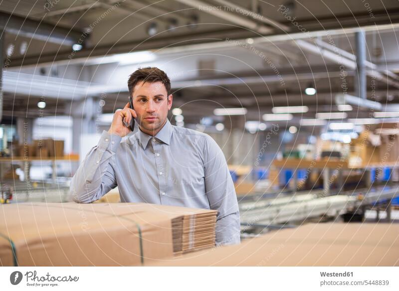 Man in factory talking on cell phone storehouse storage warehouse Businessman Business man Businessmen Business men mobile phone mobiles mobile phones Cellphone